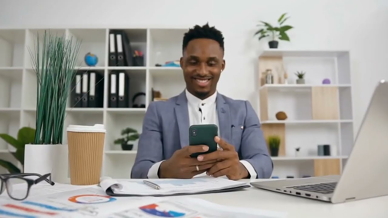 man looking at phone sitting at desk